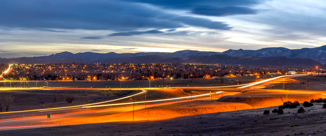 vehicles move along U.S. Highway 285 and nearby streets on a snowy evening in the winding foothills of the metro Denver area